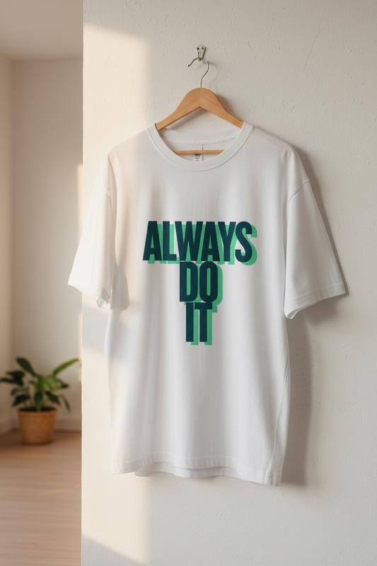 White t-shirt with 'ALWAYS DO IT' text in green on a hanger against a white wall.