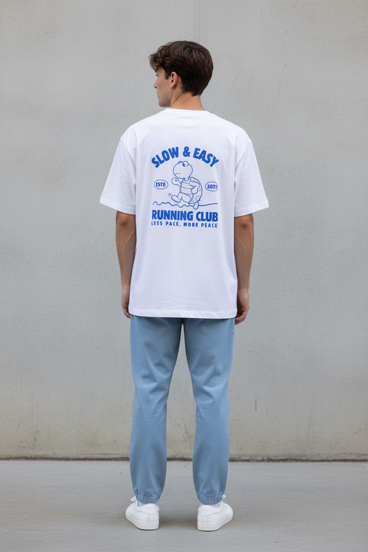 Person wearing a white t-shirt with a graphic design on the back, standing against a plain background.